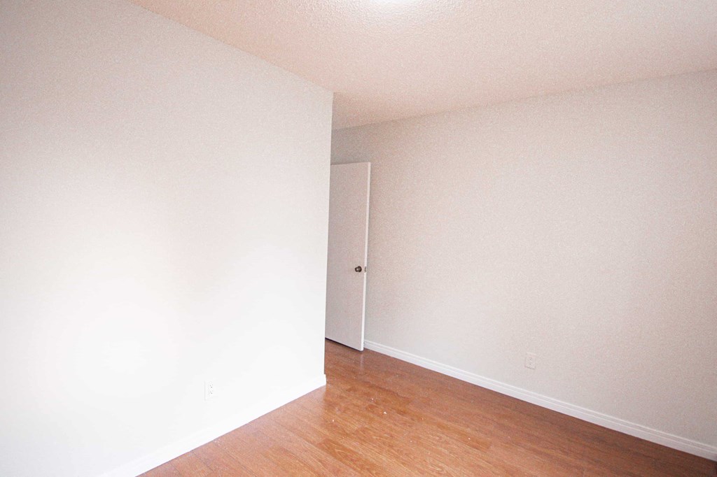 an empty room with white walls and wood floors