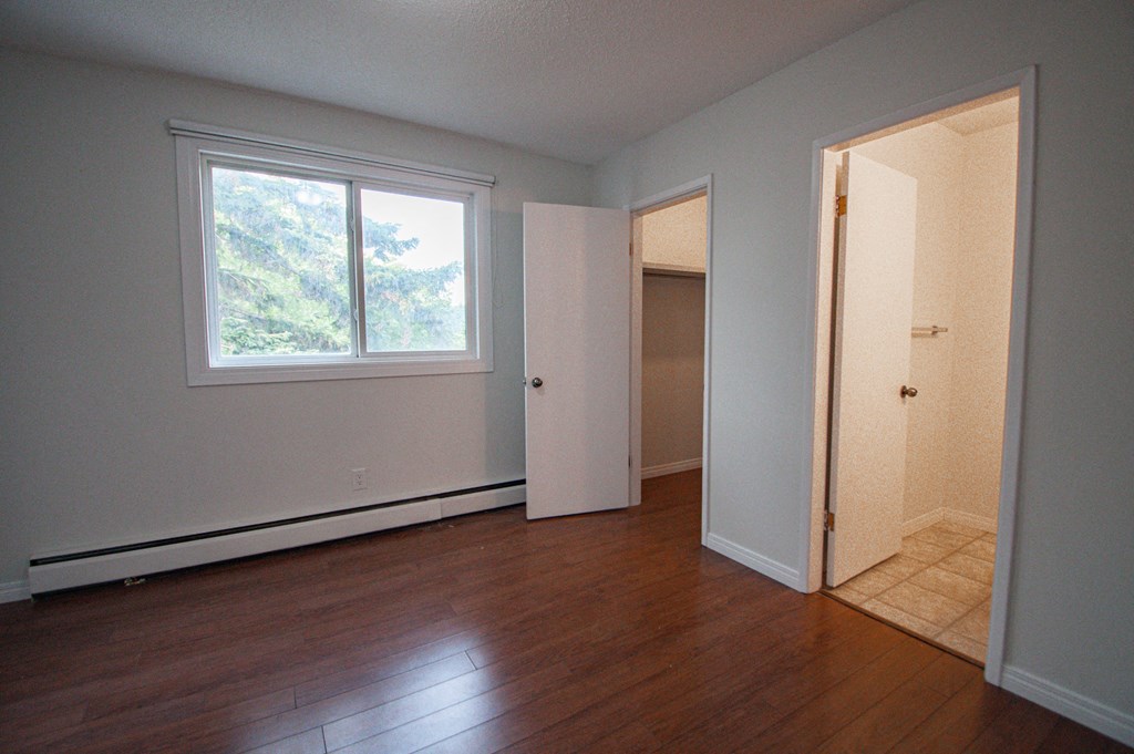 an empty room with a door to a closet and a window