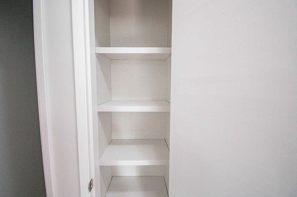 a small closet with white shelves and a white door