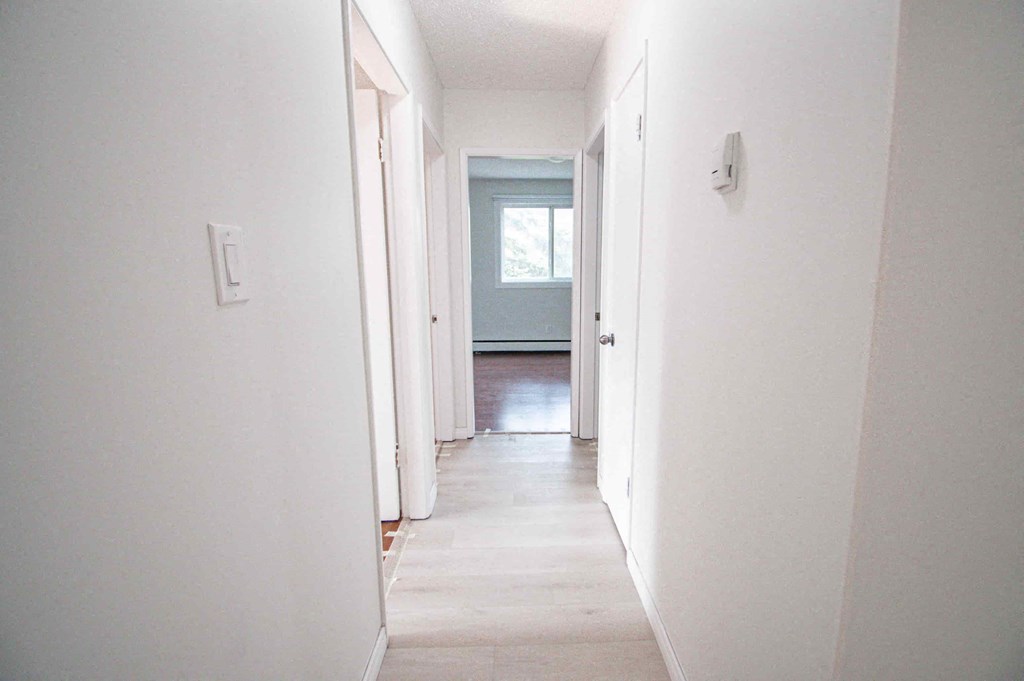 a hallway with white walls and a door to a blue room