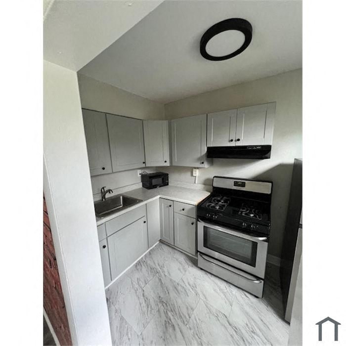 a kitchen with white cabinets and a stove and a sink