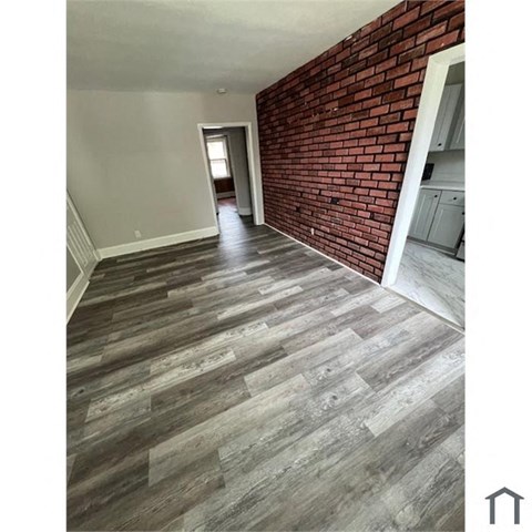 a living room with wood floors and a brick wall