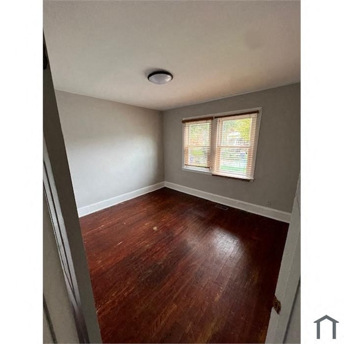 a small room with wood floors and a window