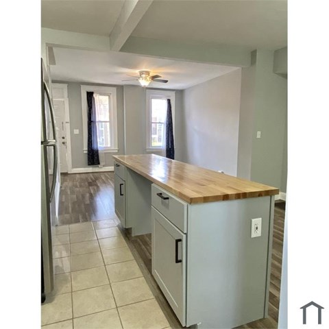 A kitchen with a wooden counter top and grey cabinets.