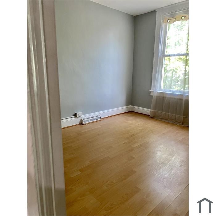 A room with wooden flooring and a window with curtains.