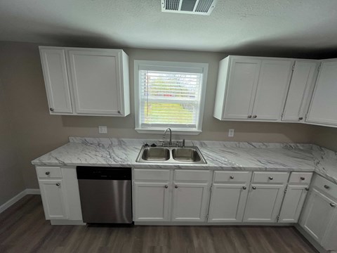 A kitchen with white cabinets and a marble countertop.