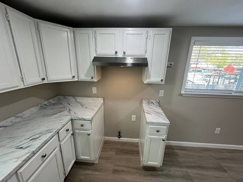 A kitchen with white cabinets and a marble countertop.