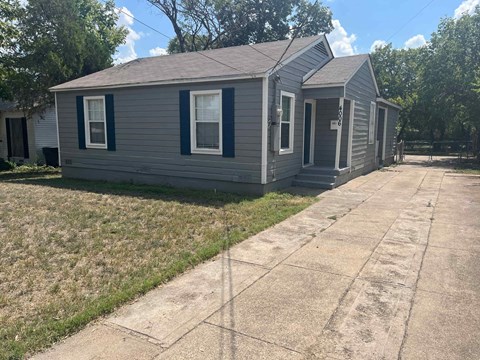 a small gray house with a sidewalk in front of it