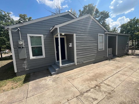 the exterior of a blue house with a driveway and a front door