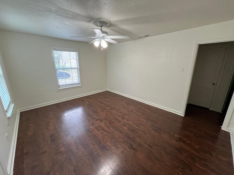 an empty living room with wood floors and a ceiling fan