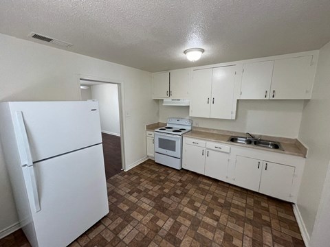 an empty kitchen with white appliances and white cabinets