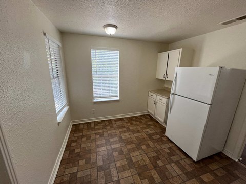an empty kitchen with a refrigerator and a window