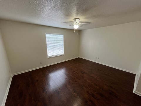 an empty living room with wood floors and a ceiling fan