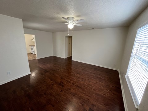 an empty living room with wood floors and a ceiling fan