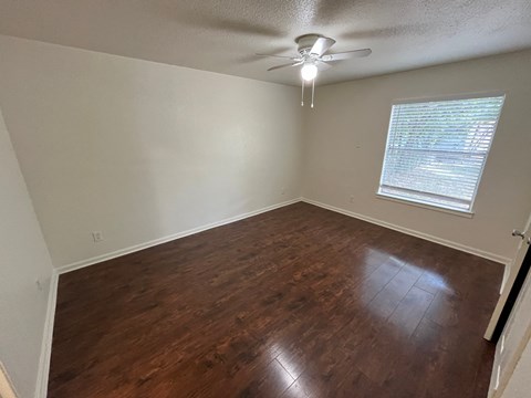 an empty living room with wood floors and a ceiling fan