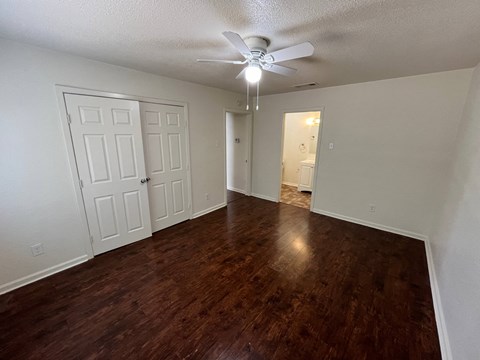 an empty living room with wood flooring and a ceiling fan