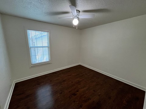 an empty bedroom with a ceiling fan and a window