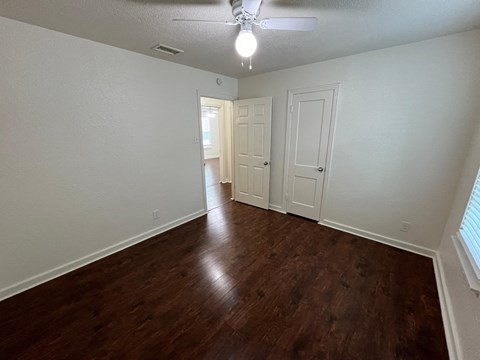 an empty living room with wood flooring and a ceiling fan