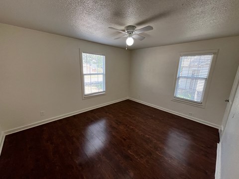 an empty living room with wood floors and a ceiling fan