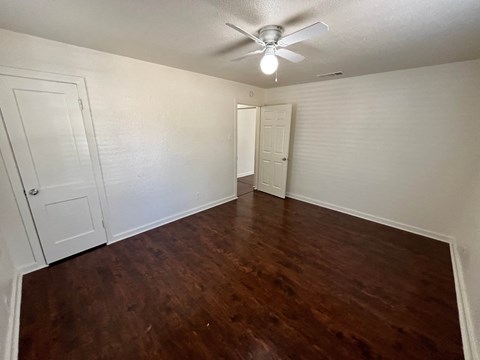 an empty living room with wood flooring and a ceiling fan