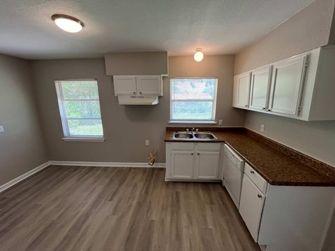 A kitchen with white cabinets and a brown countertop.