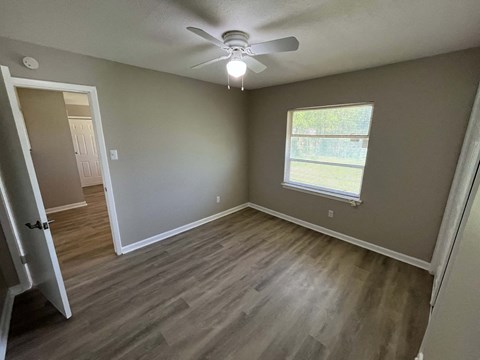 A room with a ceiling fan and a window with blinds.
