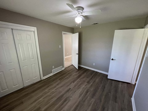 A room with a ceiling fan and wood flooring.