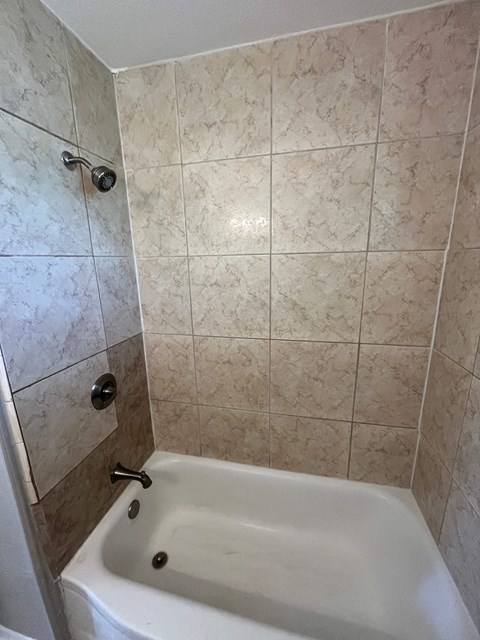 A white bathtub with a shower head and a shower curtain rod.