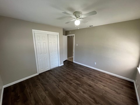 A room with a white door and a ceiling fan.