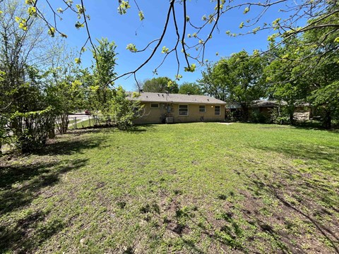 A house is surrounded by a grassy yard with trees.