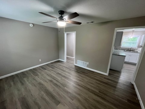 A room with a ceiling fan and wooden flooring.