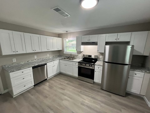 A kitchen with white cabinets and a stainless steel refrigerator.