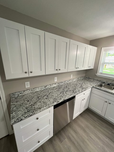 A kitchen with white cabinets and a granite countertop.