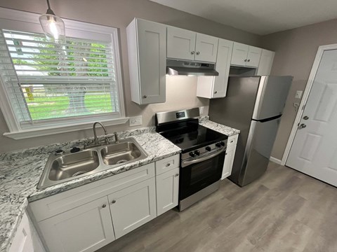 A kitchen with a sink, stove, and refrigerator.
