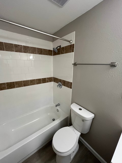 A white toilet sits next to a bathtub in a bathroom.