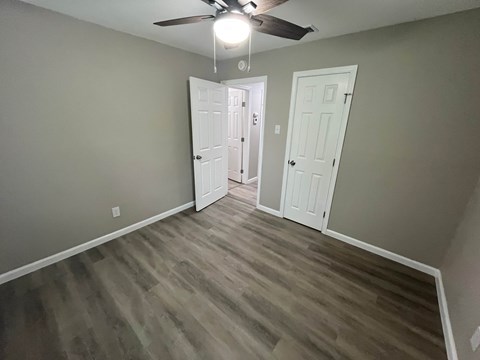 A room with a ceiling fan and two doors.