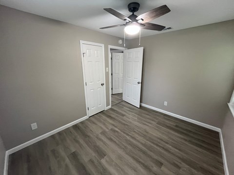 A room with a ceiling fan and two doors.