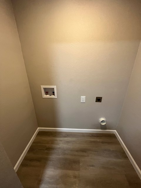 A small white square on the wall in a room with a brown floor.