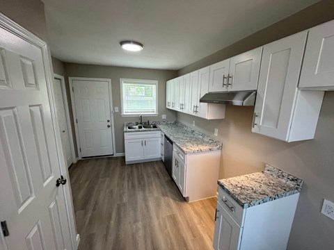 A kitchen with white cabinets and a granite countertop.