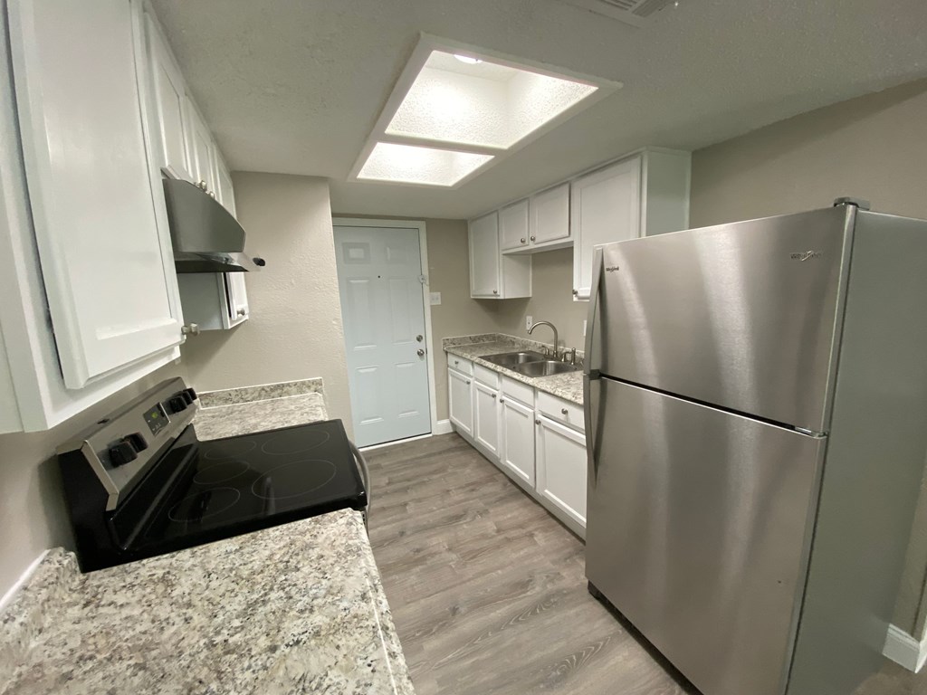 A kitchen with a black stove top oven and a stainless steel refrigerator.