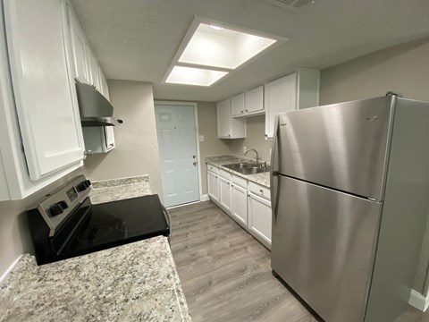 A kitchen with a black stove top oven and a stainless steel refrigerator.