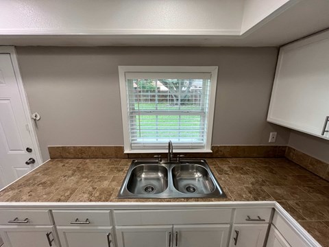 A kitchen with a double sink and a window.