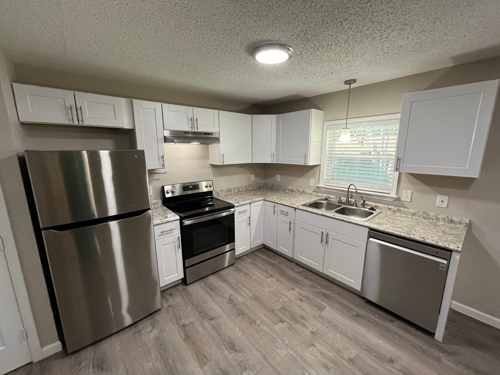 A kitchen with a stainless steel refrigerator, oven, and sink.