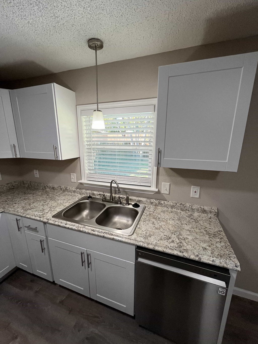 A kitchen with a granite countertop and a dishwasher.
