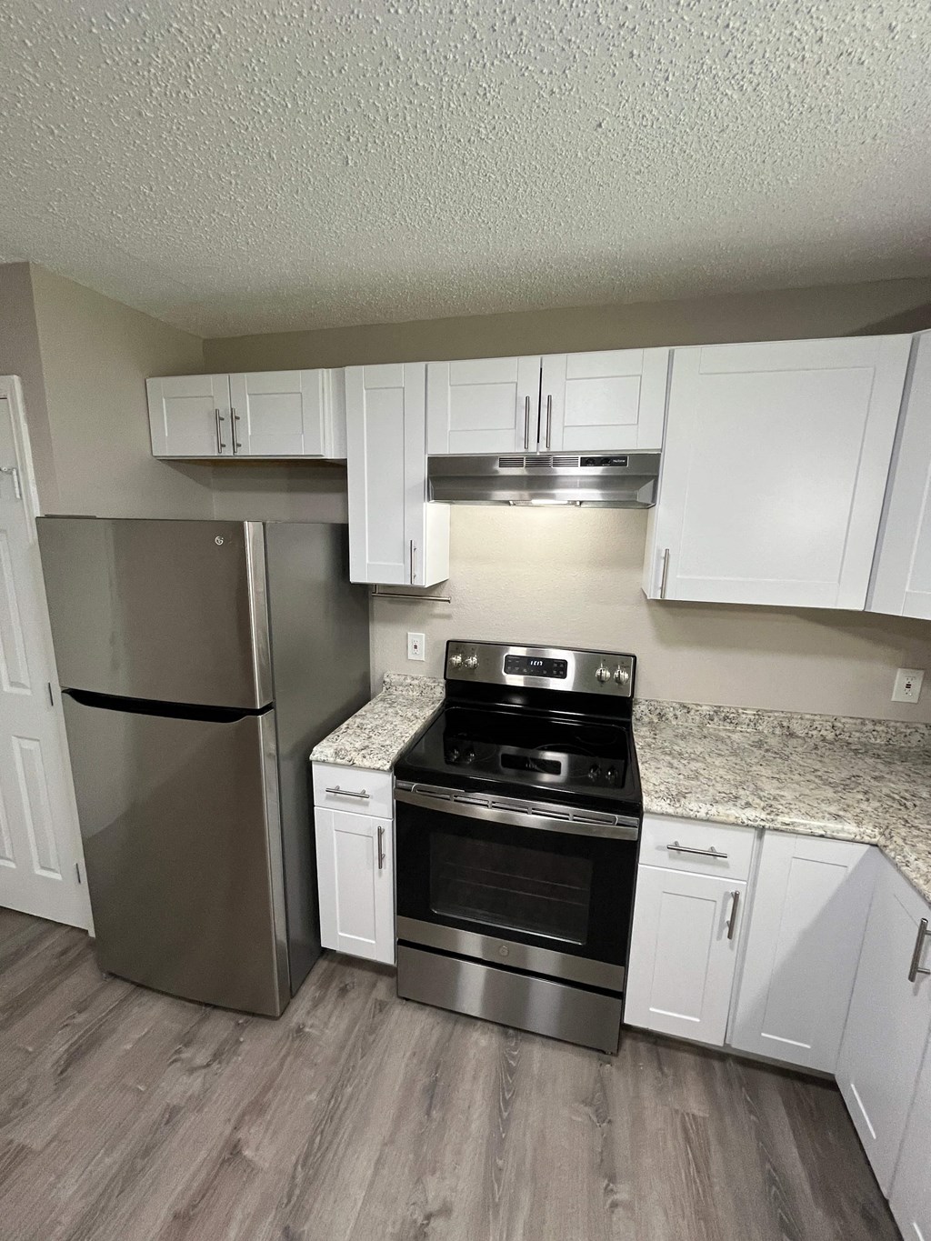 A kitchen with a stainless steel refrigerator, oven, and cabinets.