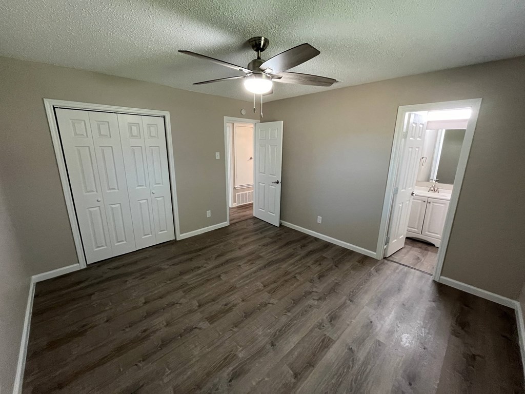 A room with a ceiling fan and wooden flooring.