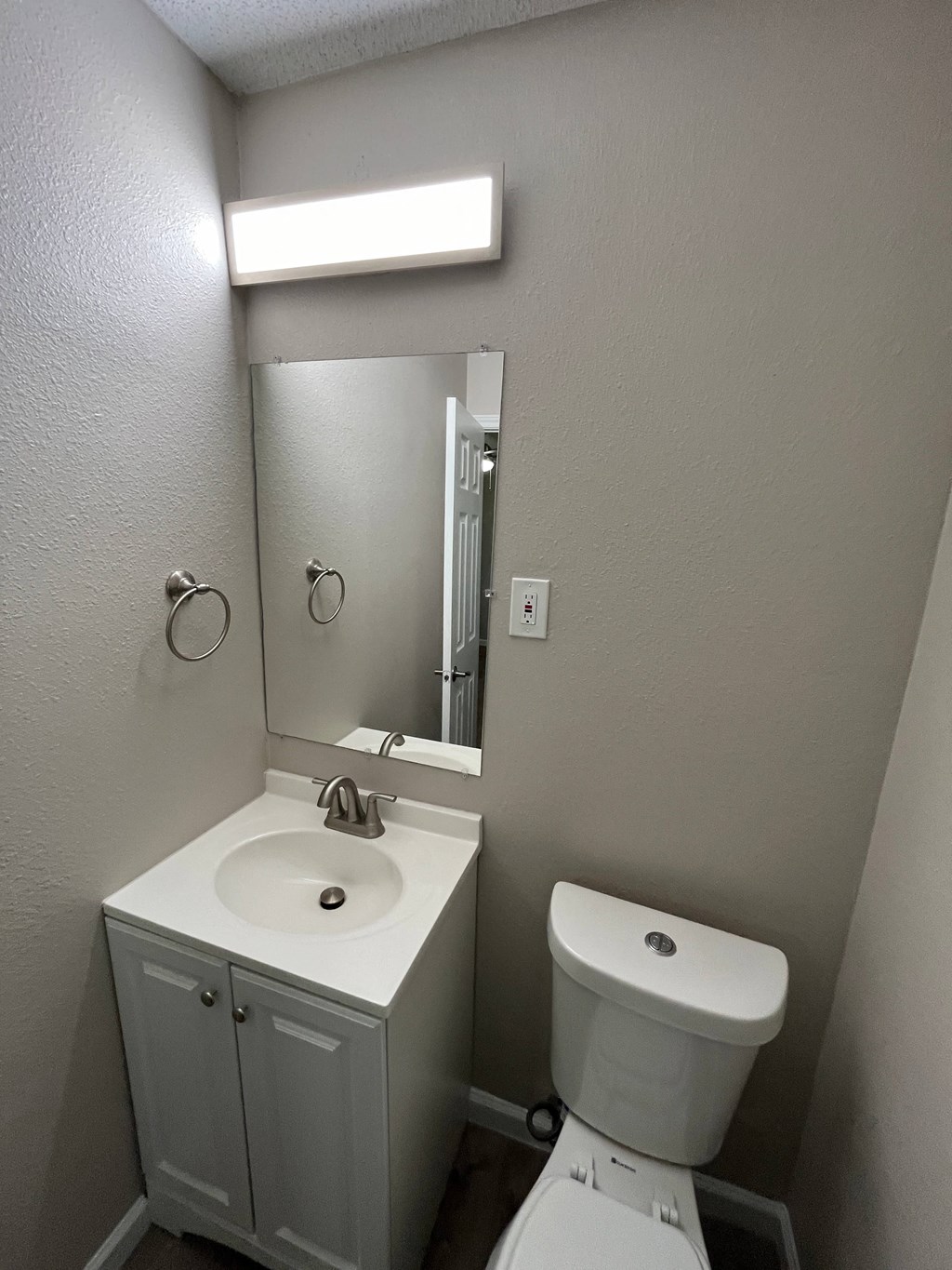 A white bathroom with a sink, toilet and mirror.