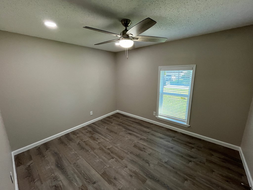A room with a ceiling fan and a window with blinds.