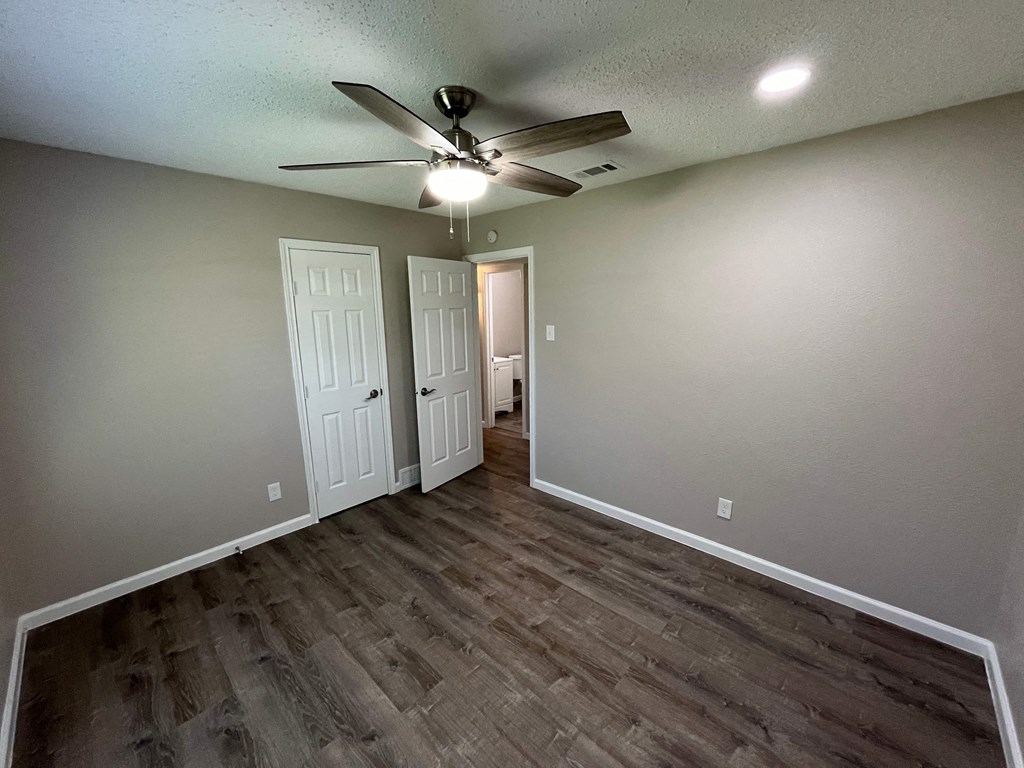A room with a ceiling fan and two doors.