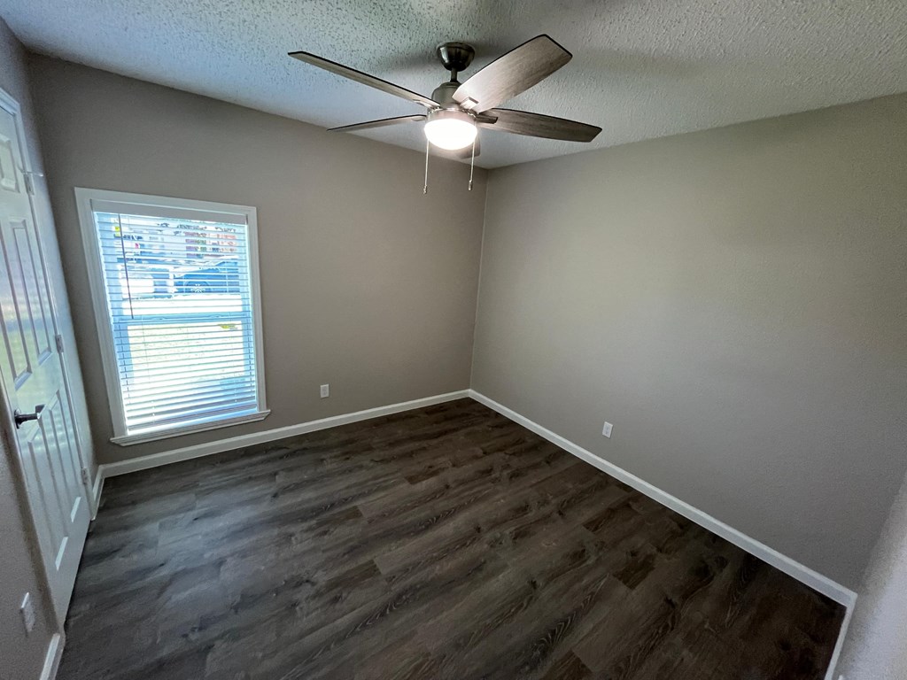A room with a ceiling fan and a window with blinds.